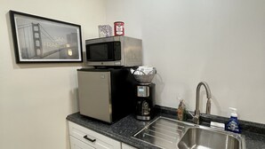 Cocina pequeña equipada con microondas, cafetera y lavamanos.