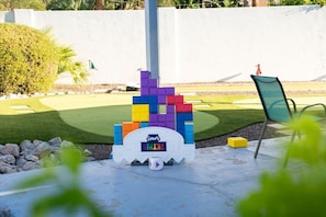A colorful play structure with a digital scoreboard, a chair, and a small pool in a backyard setting. - Home Theater | Private Pool | Hot Tub | Mini Golf (Scottsdale)