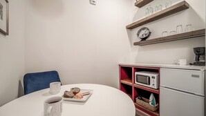 Ett litet pentry med mikrovågsugn, kaffebryggare och ett kylskåp av märket Keystone. Där finns också ett matbord med en tallrik bakverk och en kaffekopp.