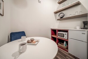 Eine kleine Küchenzeile mit Mikrowelle, Kaffeemaschine und einem Keystone-Kühlschrank. Ein Esstisch mit einer Auswahl an Gebäck und einer Kaffeetasse.