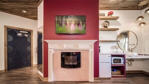 Ein modernes Interieur mit Kamin, einem darüber montierten Fernseher und einer Mikrowelle auf einer Arbeitsfläche.