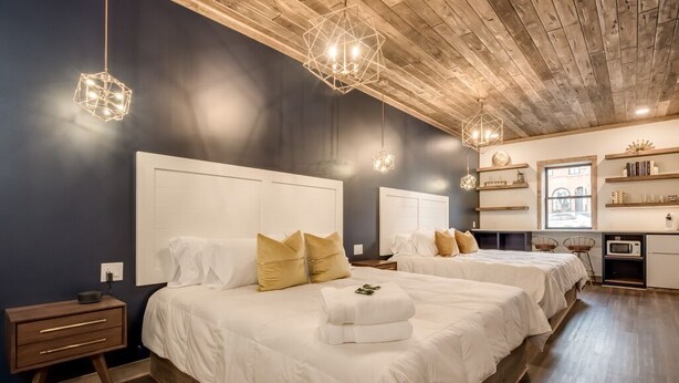 Une chambre avec deux lits, un plancher en bois et une armoire intégrée.