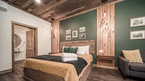 Un dormitorio con una cama de madera, cabecera de madera, una pared de acento verde y cuadros enmarcados.