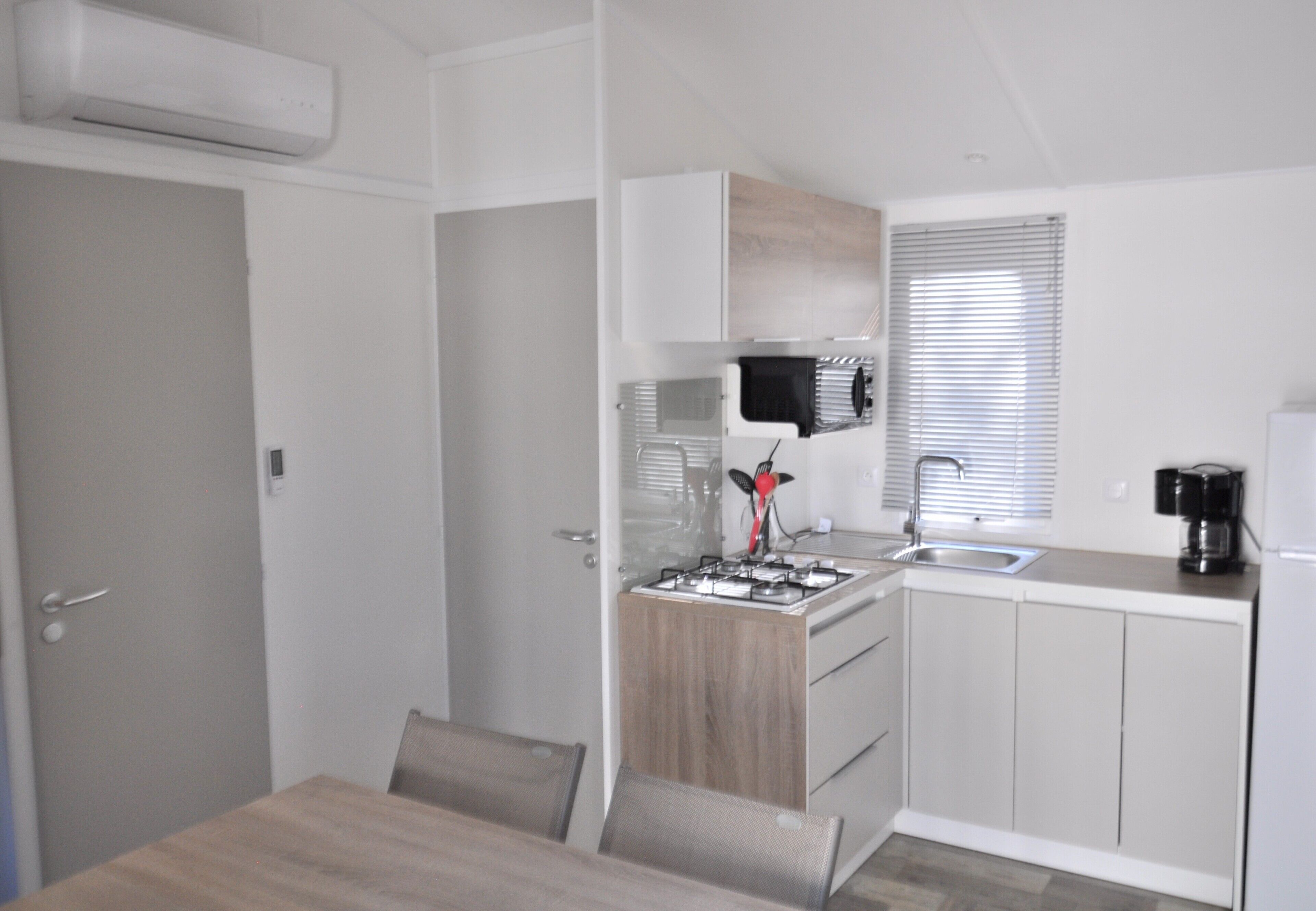 Een kleine keuken met een gasfornuis, spoelbak en moderne apparaten.