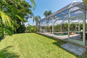 A glass-enclosed patio with a pool, surrounded by lush greenery and palm trees. - Sunset Cove - Saltwater private Pool - 1.5 miles from Siesta Key Beach (Sarasota)