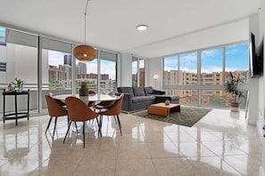 Relax in this stylish living room with expansive city views, a comfortable sofa, and a dining area.