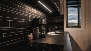 A modern kitchen with black tiled backsplash, stainless steel appliances, and a window with a view of the countryside.