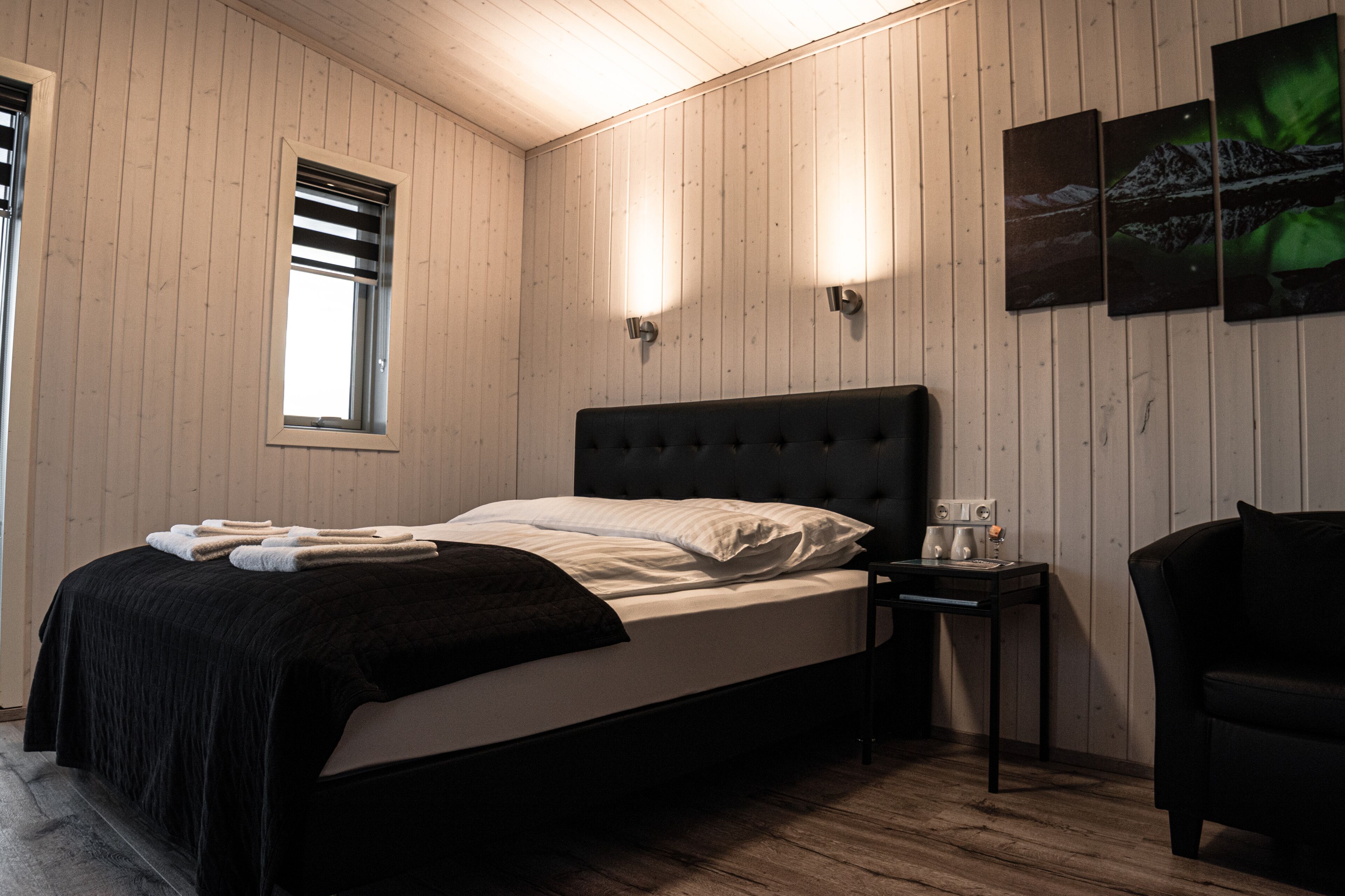 Ein Zimmer mit einem Bett, einem Nachttisch, einem Stuhl und einem Fenster mit Jalousien.