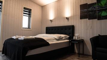 Ein Zimmer mit einem Bett, einem Nachttisch, einem Stuhl und einem Fenster mit Jalousien.