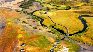 An aerial view of a rural landscape with a winding river, a small settlement with houses, and a road.