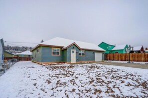 Una casa residencial con patio nevado y valla de madera.