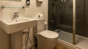 A bathroom with a sink, toilet, and glass-enclosed shower. - The wooden floors, vintage furniture, and tartan accents create a comfy room (Inverness)