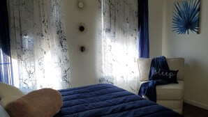 Ein Schlafzimmer mit einem Bett, einem Sessel und einer Wanddekoration.