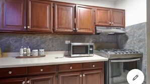 Una cocina con armarios de madera, microondas, estufa a gas y horno empotrado.