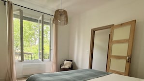 A bedroom with a bed, a chair, a window, and a door. - Gites Corbieres- rental with private pool, near Narbonne (Montséret)