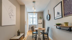 A cozy dining area with a round table, chairs, and a rug. A clock and framed artwork adorn the walls. - GuestReady - Miragaia Green (Porto)