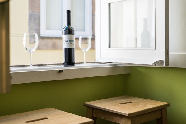 A bottle of wine and two glasses on a window sill, with a small wooden table below. - GuestReady - Miragaia Green (Porto)