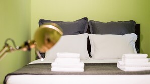 A neatly made bed with white linens and a black headboard, accompanied by a lamp on the left. - GuestReady - Miragaia Green (Porto)
