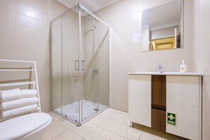 A modern bathroom with a glass-enclosed shower, a white toilet, a sink with a mirror, and a towel rack.