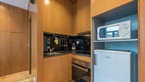 Una cocina compacta con armarios de madera, un microondas, una estufa y un refrigerador.