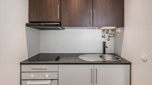 Una cucina compatta con mobili da cucina in legno scuro, un lavello in acciaio inossidabile e un forno integrato.