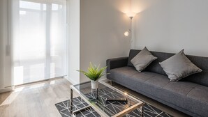 Un soggiorno moderno con un divano grigio, un tavolino in vetro e una lampada da terra.