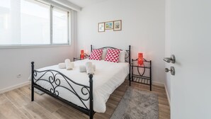 Quarto com cama, mesa de cabeceira, janela e porta.