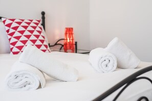 A neatly made bed with two rolled white towels and a red and white patterned pillow. - GuestReady - Retreat near Matosinhos beach (Matosinhos)
