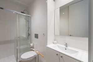 A modern bathroom with a glass-enclosed shower, a white sink, and a large mirror. - GuestReady - Retreat near Matosinhos beach (Matosinhos)