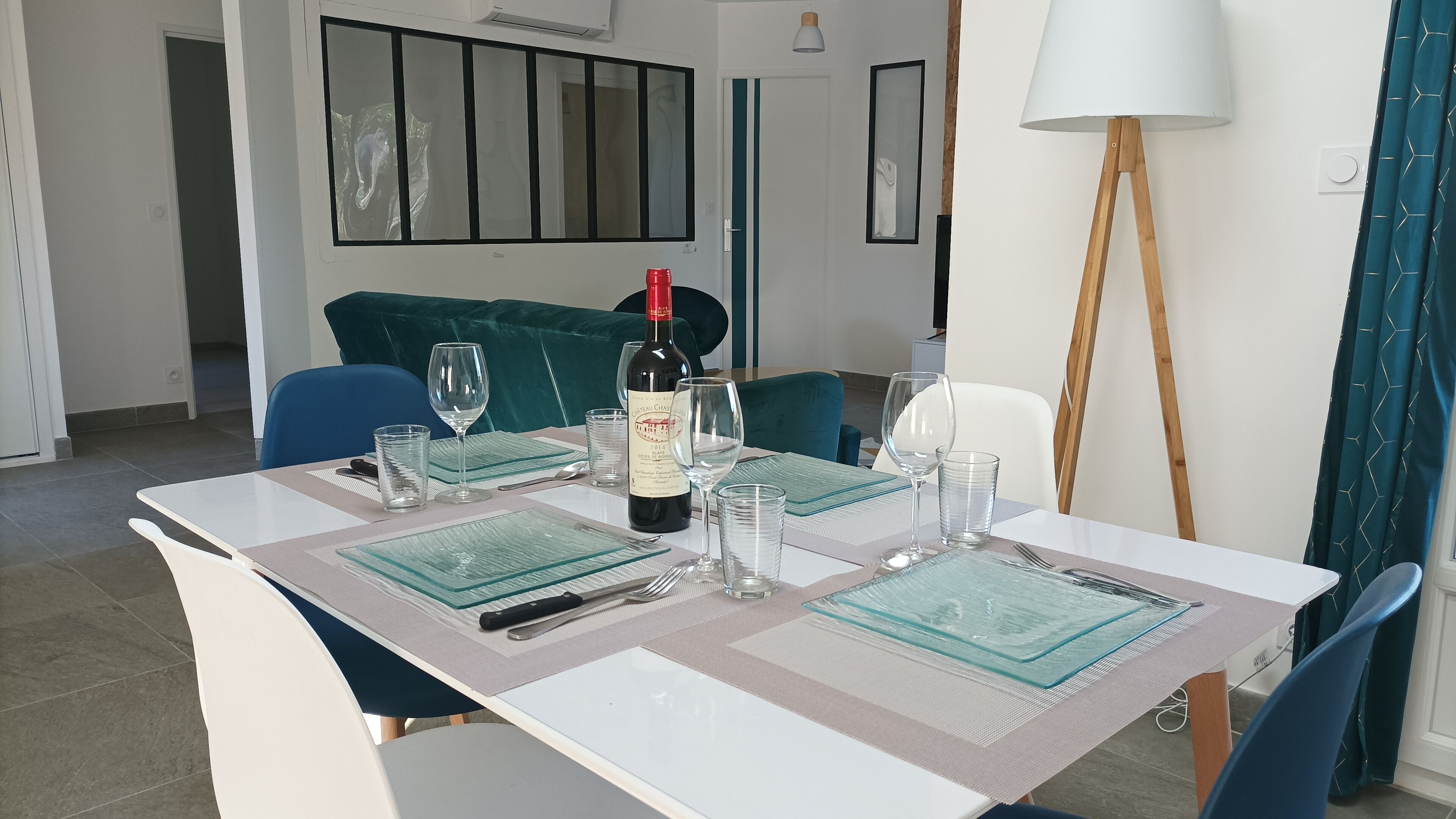 A dining table set with wine glasses, a bottle of wine, and cutlery.