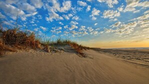 A beach with sand dunes and sparse vegetation under a partly cloudy sky. - Marriott's Surf Watch - Luxury 2 BR, 2 Bath Villa w/ full kitchen that sleeps 8! (Hilton Head Island)