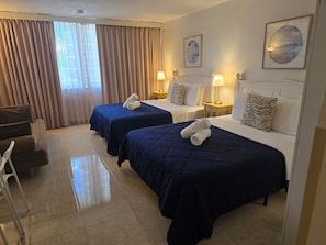 Una habitación de hotel con dos camas, un sofá, una silla y un ventanal con cortinas.