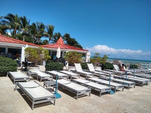 Resort com espreguiçadeiras ao ar livre e um edifício com telhado vermelho.