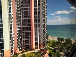 Hotel alto com várias varandas com vista para uma praia e oceano.