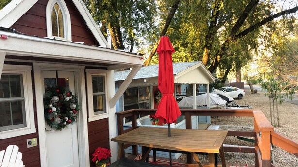 A wooden deck with a table and chairs, a red umbrella, and a Christmas wreath on the door. - ALL INCLUSIVE AMENITIES:Kayak,SUP,Pedal Boat,PingPong,Pickleball,Movie Nt &MORE! (Nice)