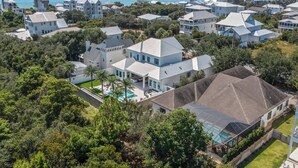 A coastal residential area with multiple white houses, a swimming pool, and a view of the ocean. - Better on Brenda | Private Pool + Spa | Private Beach Access | 4 Bikes (Seacrest)