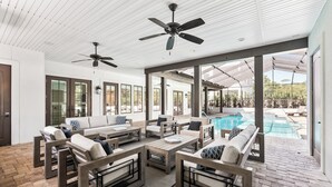 A spacious patio area with outdoor furniture, a ceiling fan, and a view of a swimming pool. - Better on Brenda | Private Pool + Spa | Private Beach Access | 4 Bikes (Seacrest)