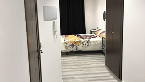 Een hotelkamer met een bed, een kledingkast, een telefoon en een gordijn.