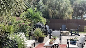 Un patio con mobiliario exterior, plantas en macetas y un hogar para la chimenea.