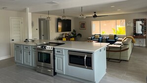 Una cocina moderna con una isla central, hornos integrados y un amplio ventanal que proporciona luz natural.