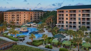 Un hotel con varias plantas, piscina y zonas de estar al aire libre.