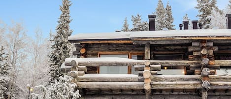 Una baita di legno con tetto innevato, pareti in legno e un camino.