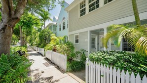 A row of white houses with a white picket fence, lush greenery, and a clear sky. - **SERENITY ON SOUTHARD @ THE ANNEX** Condo + Last Key White Glove Service... (Key West)