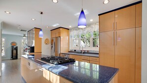 Una cocina moderna con armarios de madera, encimera de granito e iluminación colgante.