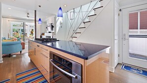 Una cocina moderna con una isla grande, horno empotrado y una escalera con barandilla.