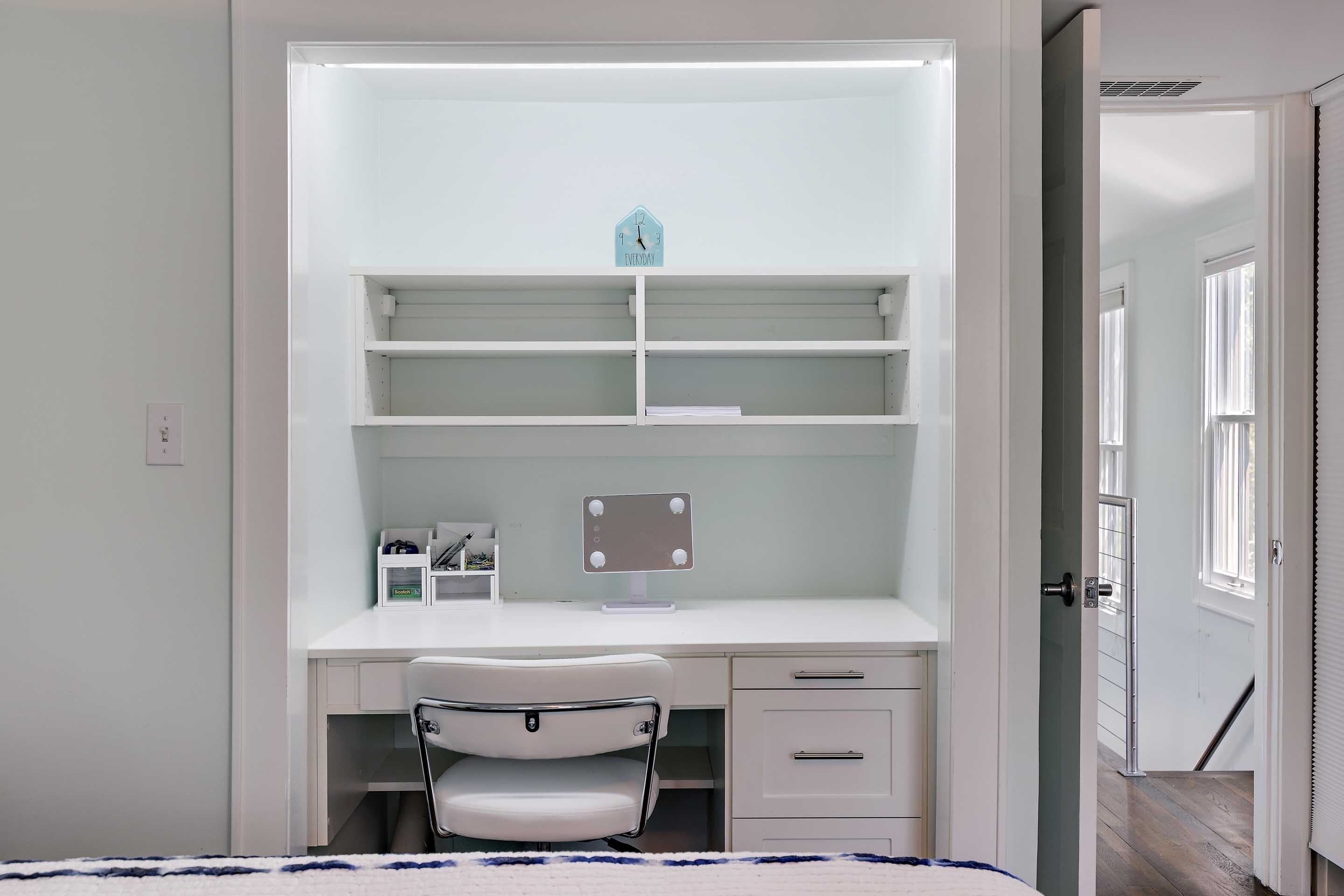 A bedroom with a bed, a desk with a chair, a wardrobe, and a door leading to another room.