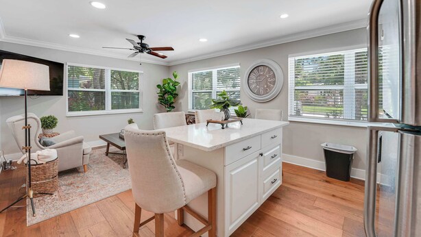A modern kitchen with white cabinetry, a central island, and a dining area with a chair and table.
