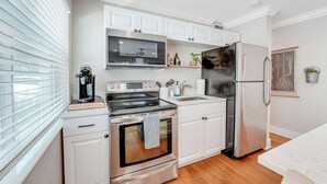 A modern kitchen with white cabinets, stainless steel appliances, a microwave, oven, and refrigerator.