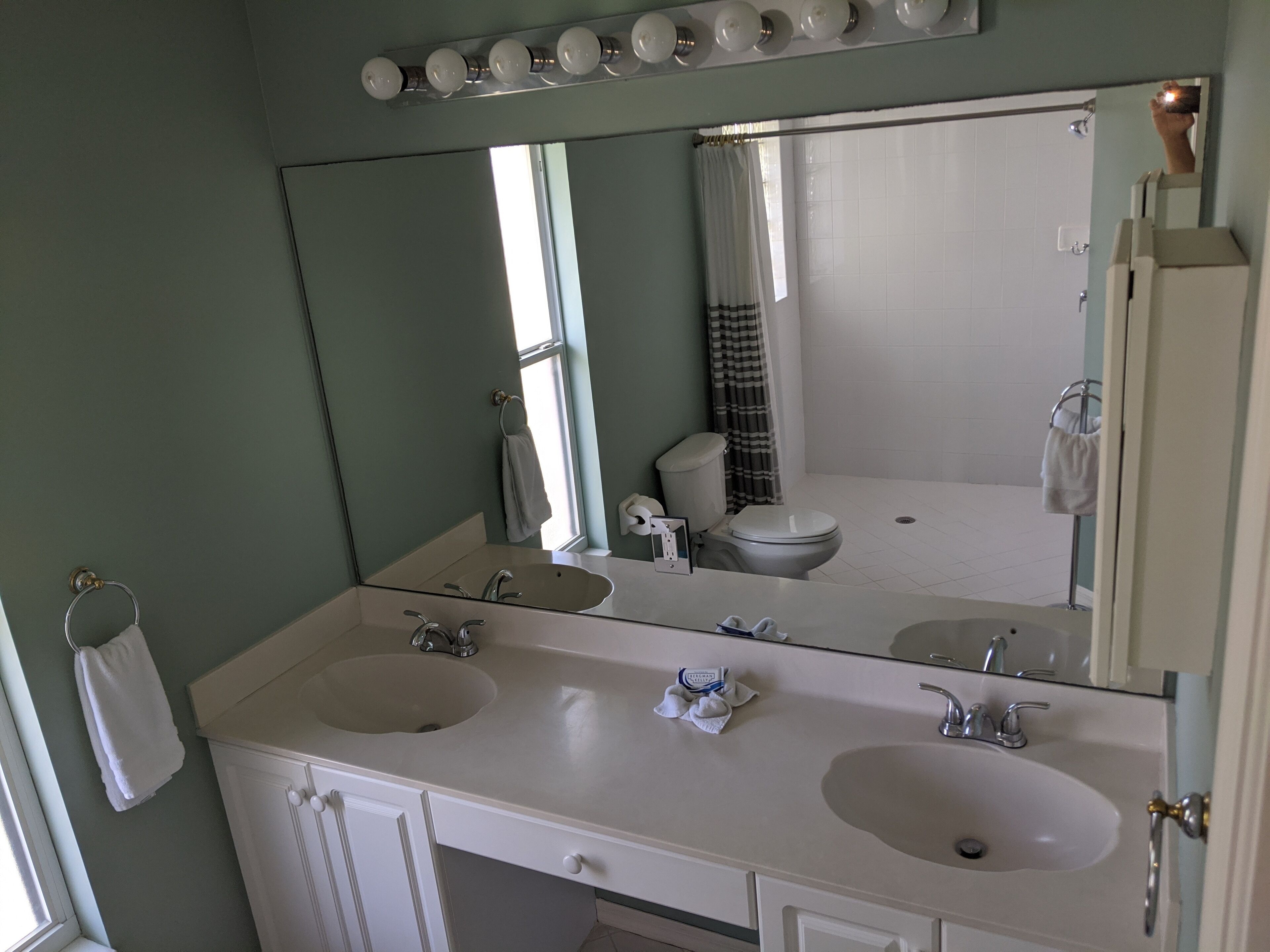 Un baño con dos lavamanos, un espejo grande y una cortina de ducha.