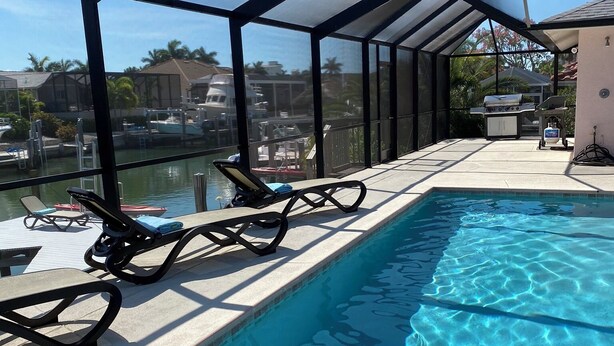 Ein Schwimmbecken mit Liegestühlen und einer überdachten Terrasse.